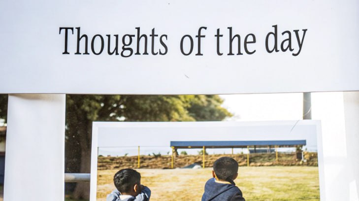 Signboard with the heading “Thoughts of the day” displayed above a picture of two young children looking into the distance in an outdoor setting.