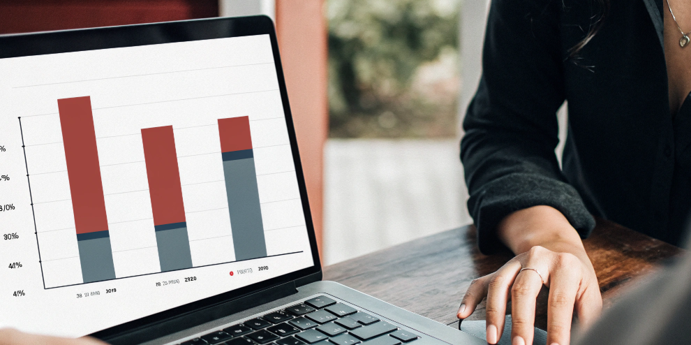 Student analyzing a bar chart on a laptop screen, comparing data trends from 2019 to 2021 for exam results and performance statistics.