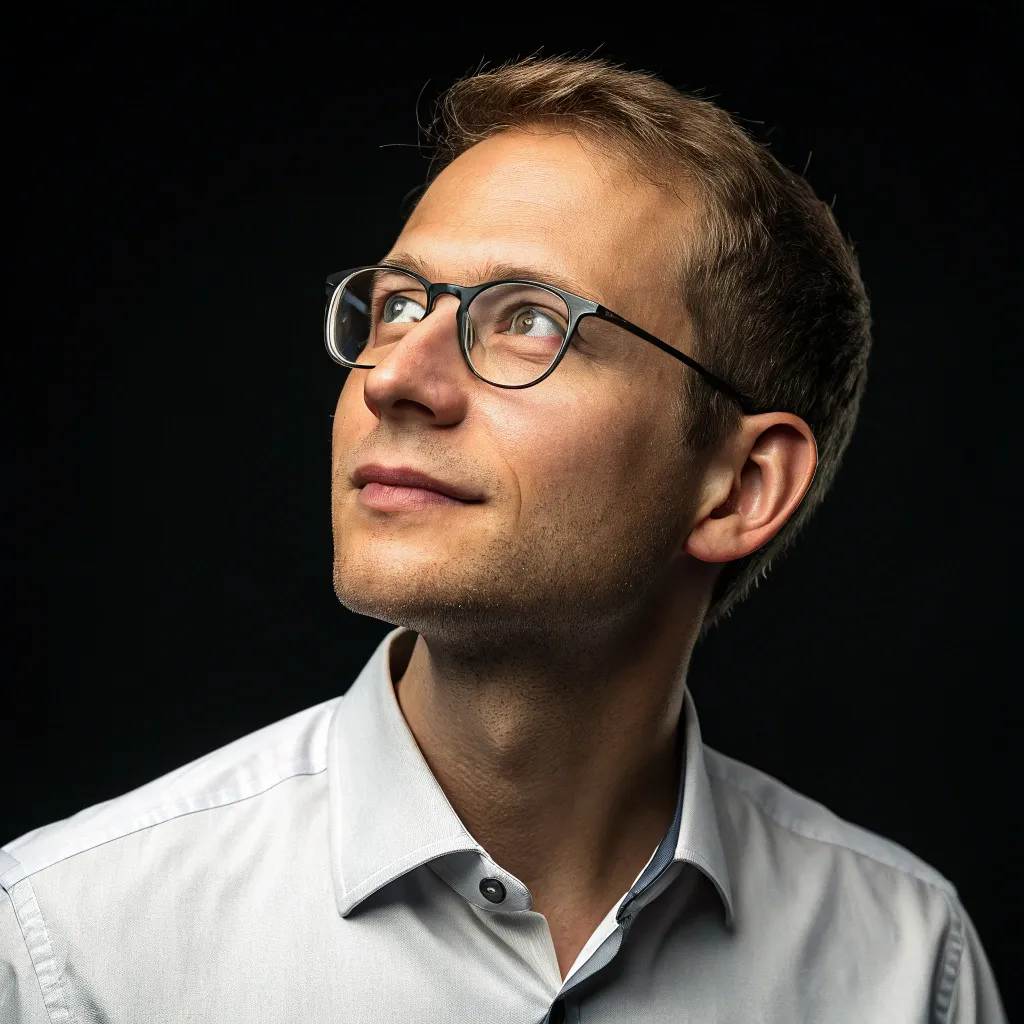 olivier-rousseau Professional headshot of Olivier Rousseau, a light-skinned man with glasses, short hair, and a white shirt, looking thoughtfully against a dark background.